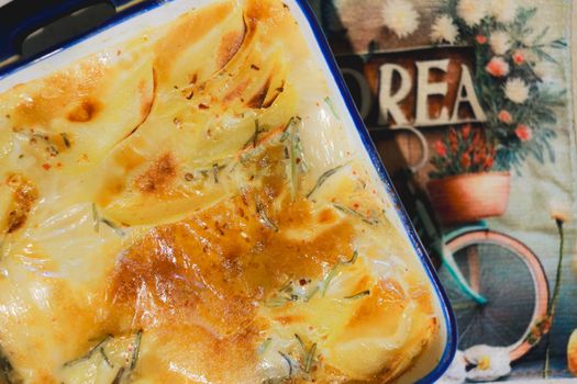 Gratin de chou blanc et bacon doré, servi dans un plat en céramique, avec un torchon décoratif en arrière-plan.