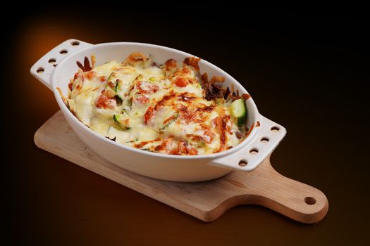 Gratin de chou blanc et bacon doré, servi dans un plat en céramique sur une planche en bois.